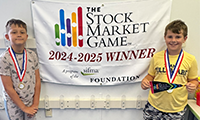  Two students wearing gold medals in front of a banner which reads The Stock Market Game Winners